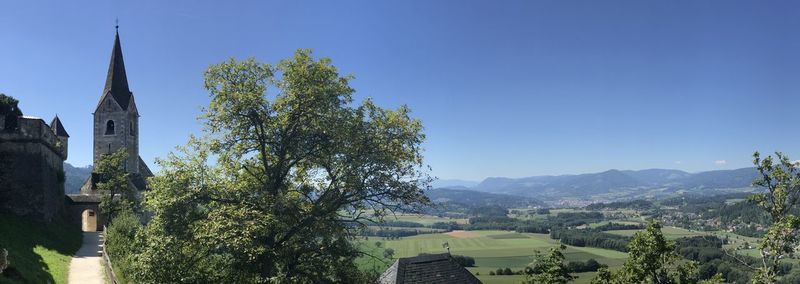 Panoramic view of trees and buildings against clear blue sky