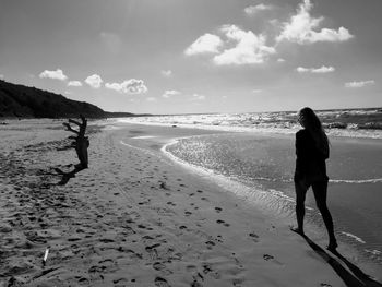 Rear view of silhouette woman walking at beach against sky