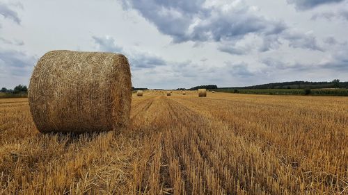 Hay bales on field against sky