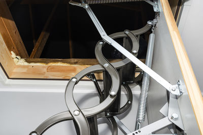 A spring tensioning mechanism that facilitates the opening of a metal ladder to the attic. 