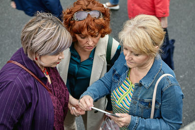 Women looking at mobile standing outdoors