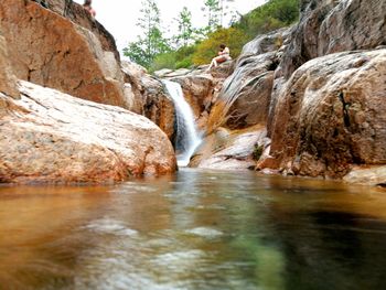 Scenic view of waterfall by river against sky
