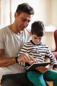 Father using tablet with son at home