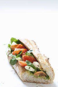 Baguette with mozzarella and tomatoes on white background