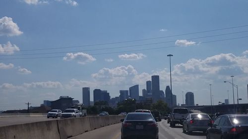 Cars on road by buildings against sky