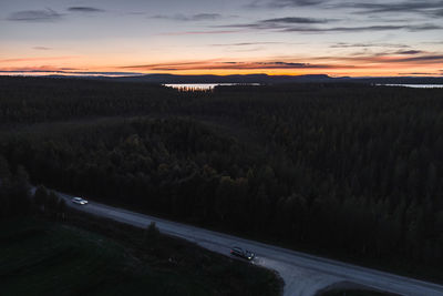 Road by landscape against sky during sunset