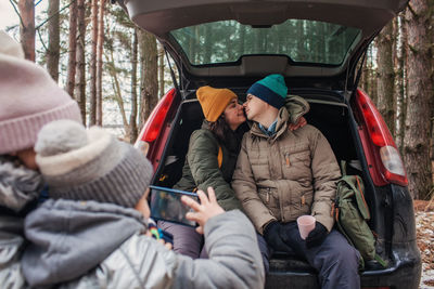 Winter family road trip. happy parents with kids make photo in the trunk of car