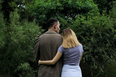 Rear view of couple standing against trees