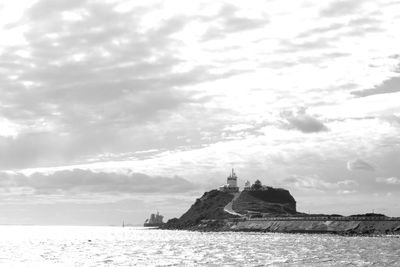 Lighthouse by sea against sky