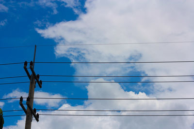 Low angle view of power lines against blue sky