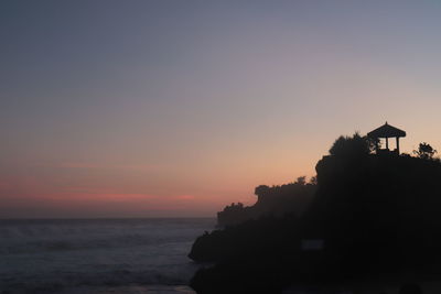 Silhouette beach by sea against sky during sunset