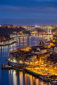 Illuminated buildings by river against sky in city at night