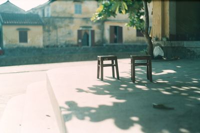 Empty chairs and table in yard of house