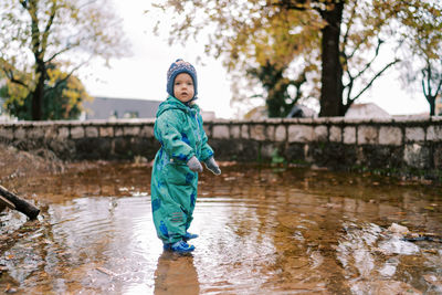 Portrait of young woman standing on puddle