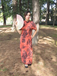 Portrait of a smiling young woman standing against trees