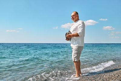 Happy middle-aged bearded man walking along beach. concept of leisure activities, wellness, freedom