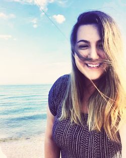 Portrait of smiling young woman against sea