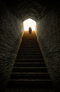 Low angle view of person walking on staircase in tunnel