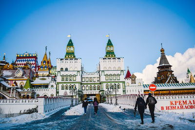 People on snow covered buildings in city