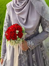 Midsection of bride holding bouquet