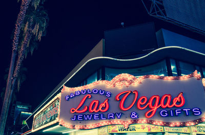 Low angle view of illuminated information sign in city at night