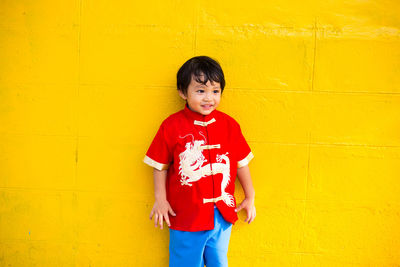 Cute smiling boy standing against yellow wall