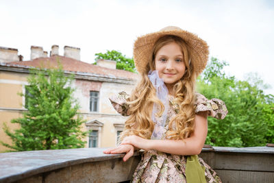 Little girl in dress and hat posing on the balcony