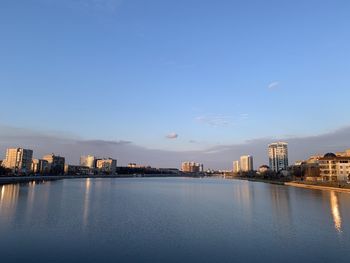 Scenic view of river by buildings against blue sky