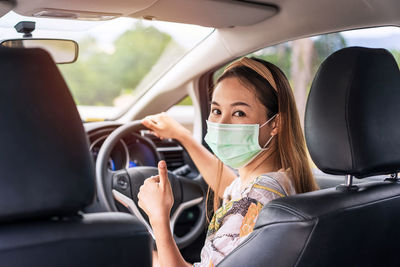 Portrait of woman wearing mask sitting in car