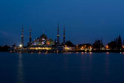 Illuminated buildings against clear sky at night