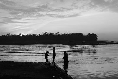 Silhouette people on beach against sky