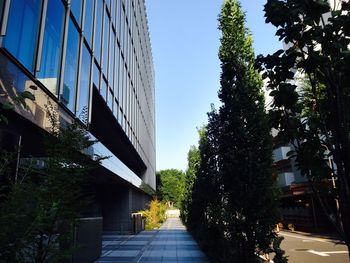 Low angle view of cropped glass structure against clear blue sky