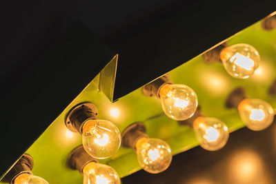 Low angle view of illuminated light bulb hanging on ceiling