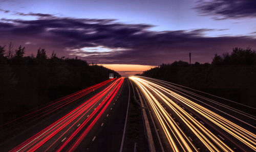 Light trails on road against sky at night