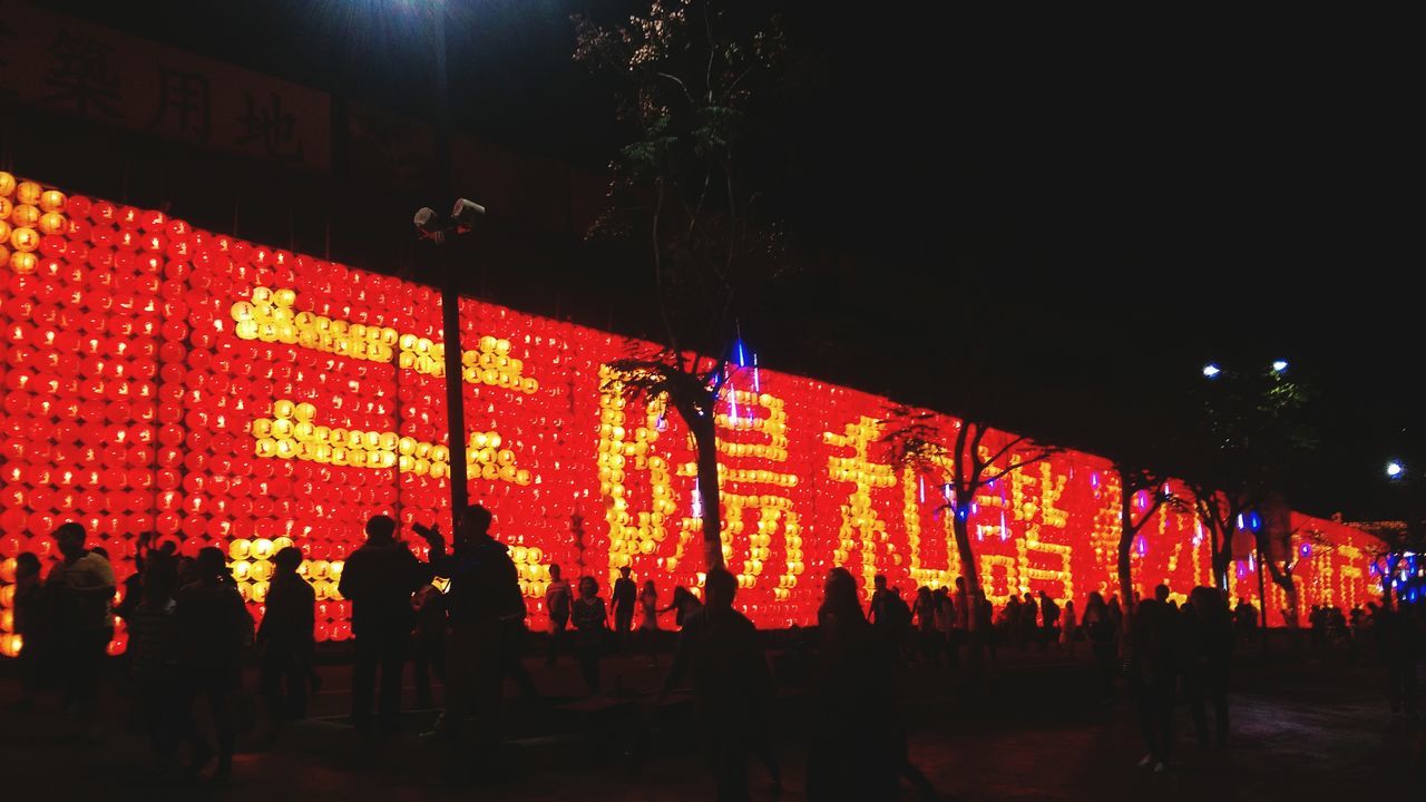 illuminated, night, large group of people, text, person, men, lifestyles, crowd, celebration, leisure activity, multi colored, western script, non-western script, lighting equipment, red, street, communication, store, city life