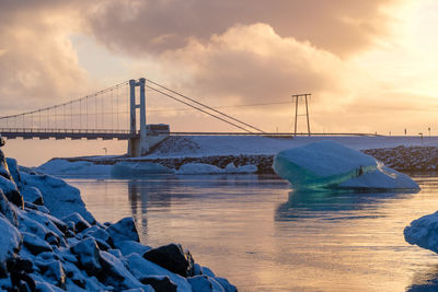 Bridge over sea against sky during sunset