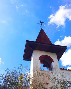 Low angle view of cross by building against sky