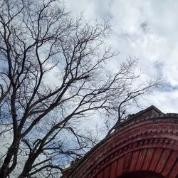 Low angle view of bare tree against cloudy sky