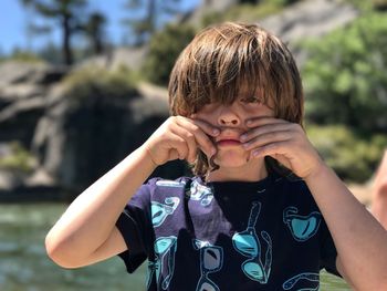 Boy holding worm around mouth as mustache