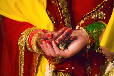 Cropped image of bride and groom holding hands during wedding