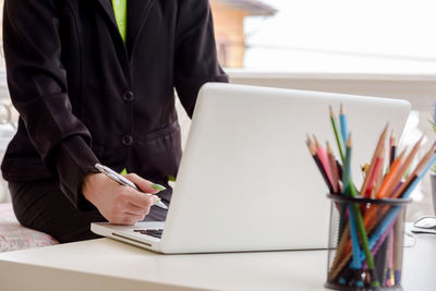 Midsection of man using laptop on table
