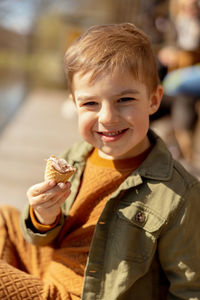 Little adorable boy sitting outdoors and eating ice cream. lake, water and sunny weather. 