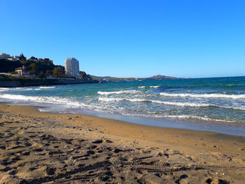 Scenic view of beach against clear blue sky