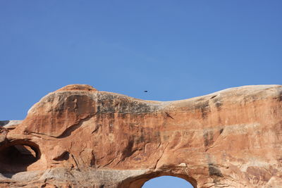 Low angle view of rock formation against clear blue sky