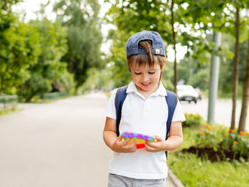 Little boy plays square rubber fidget toy pop it. rainbow-colored anti stress toy for all ages. 