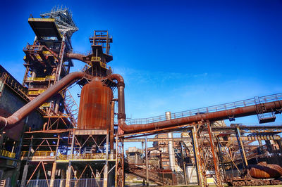 Low angle view of industry against blue sky