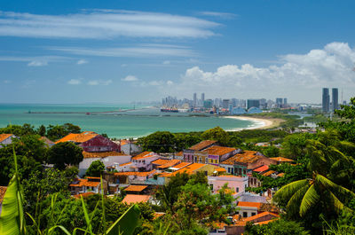 High angle view of city by sea against cloudy sky