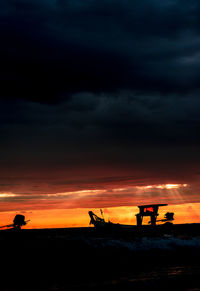 Silhouette beach against dramatic sky during sunset