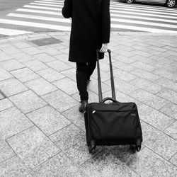 Low section of woman with luggage on pavement