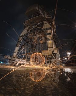 Illuminated ferris wheel against sky at night